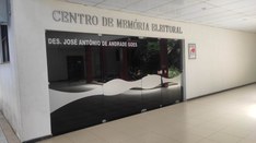  Foto da entrada do Centro de Memória Eleitoral com quatro portas em vidro fumê, contendo o nome...