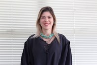 Foto de busto colorida da Juíza Ouvidora Dauquiria de Melo Ferreira, usando toga, cabelos loiros...